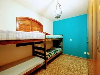 Clínica de Recuperação em Itaúna - MG Quarto com dois beliches de madeira, parede azul-turquesa e guarda-roupa de portas de madeira
